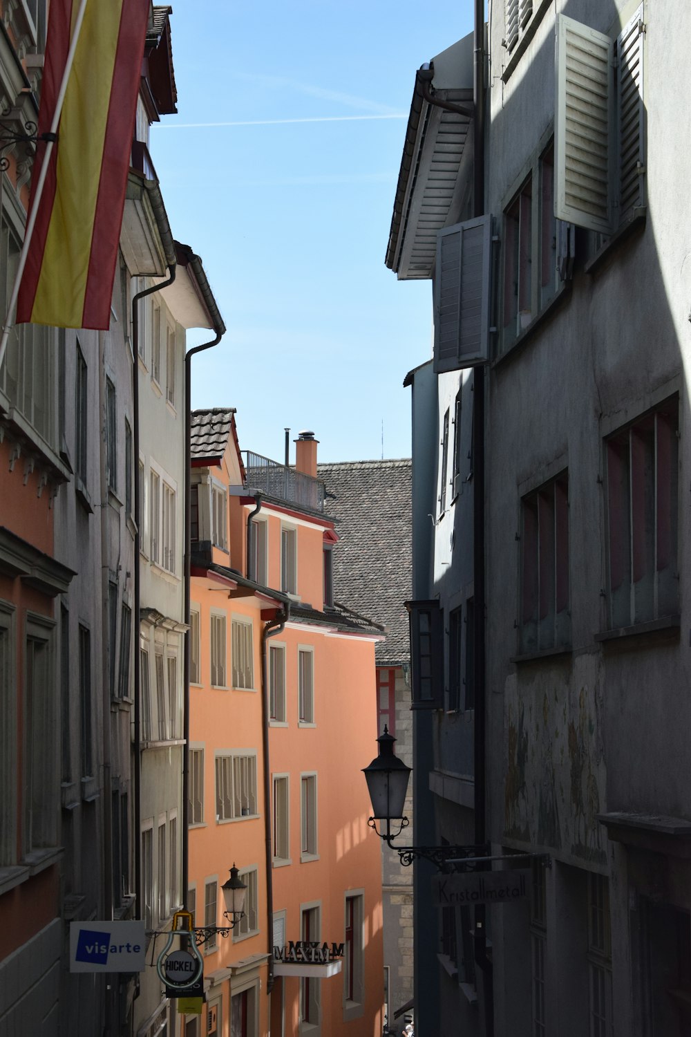 a narrow city street with buildings and a flag