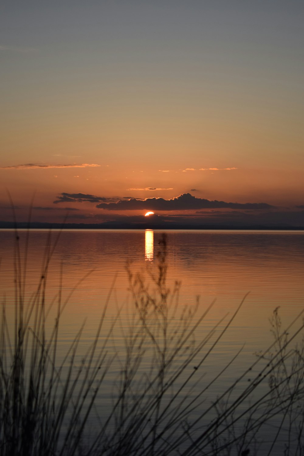 the sun is setting over a calm lake