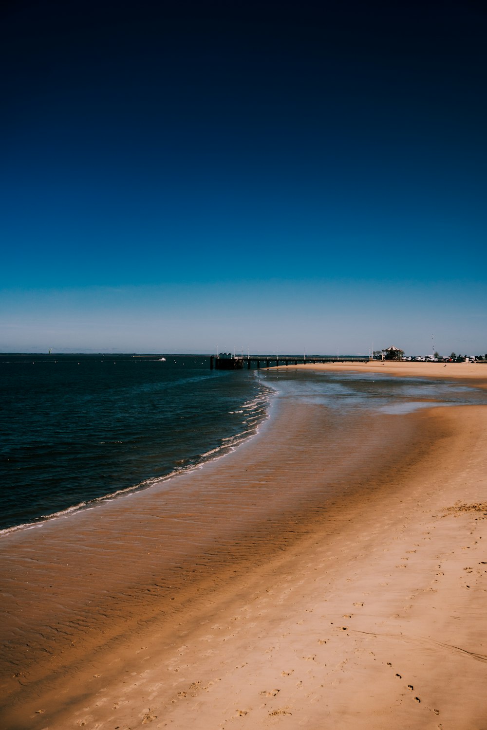 a sandy beach next to the ocean under a blue sky