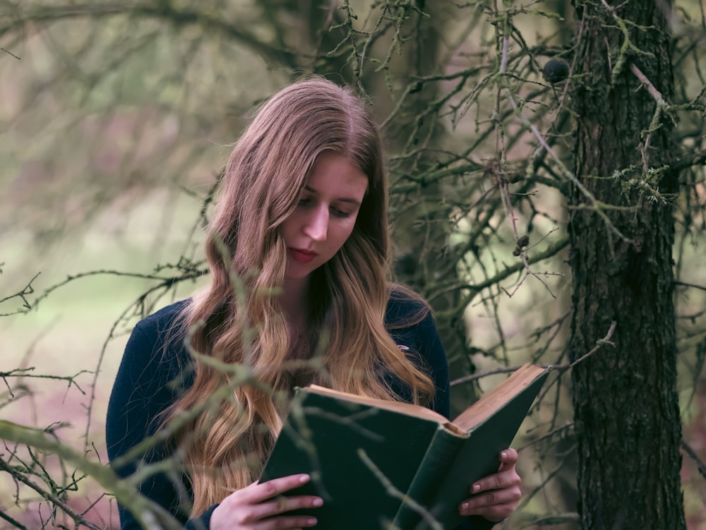 a woman is reading a book in the woods