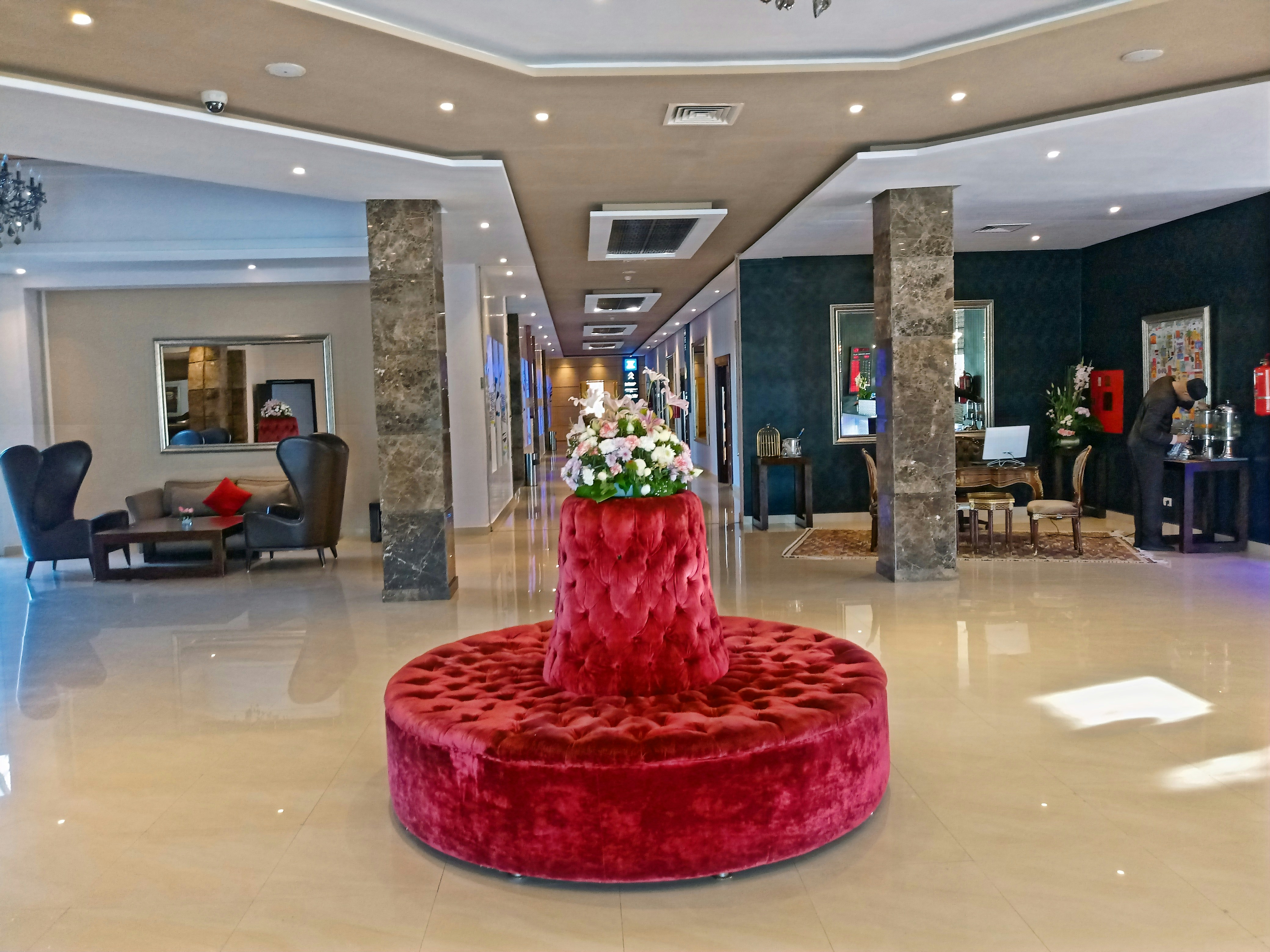 Boutique hotel lobby renovation with deep burgundy tones, dim mood lighting and velvet seating