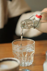 a person pouring water into a glass on a table