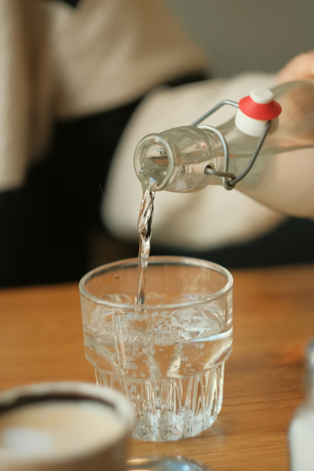 a person pouring water into a glass on a table
