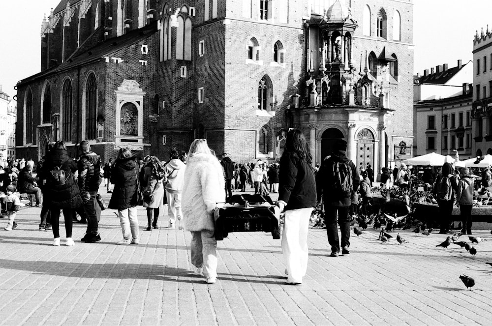 Una foto en blanco y negro de personas caminando frente a una iglesia