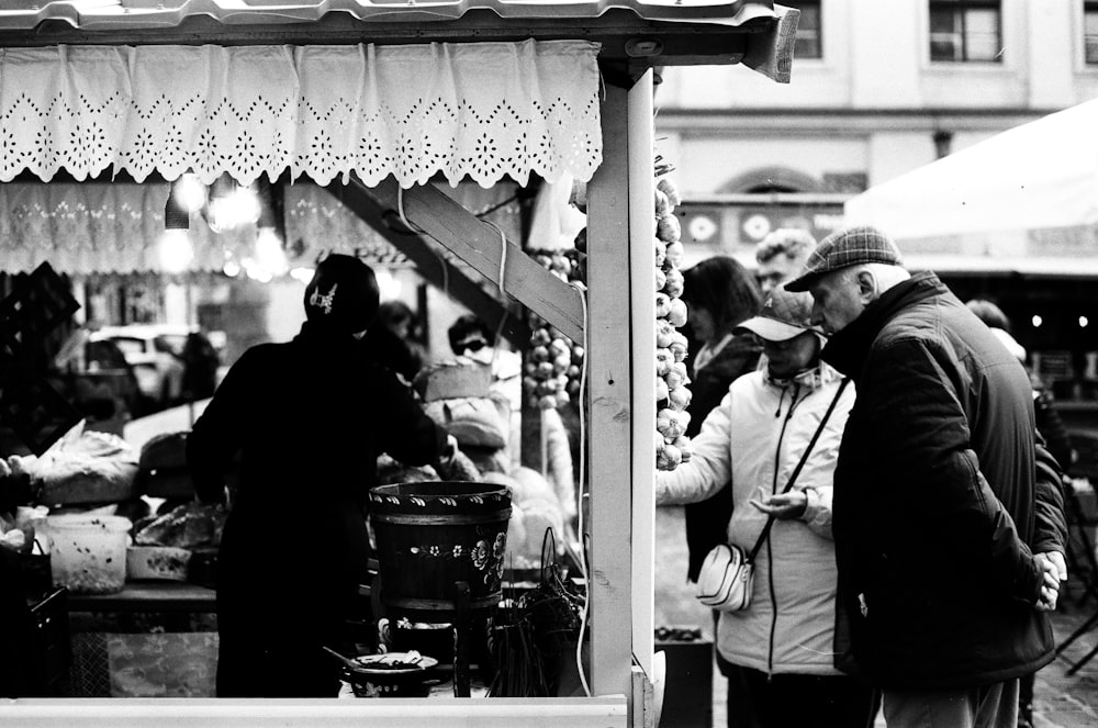 a group of people standing around a food stand