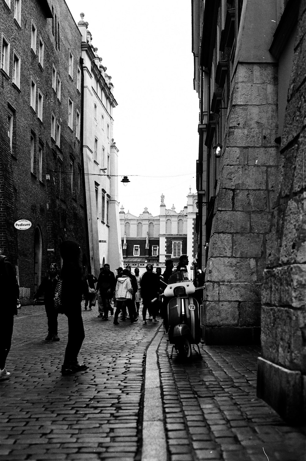 a group of people walking down a street next to tall buildings