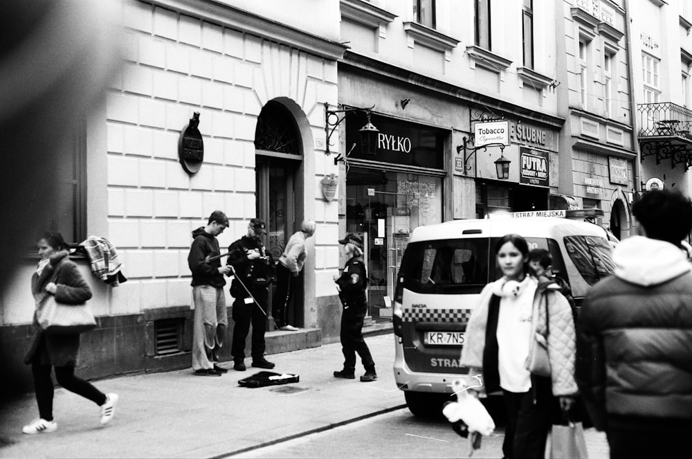 a group of people walking down a street next to a van