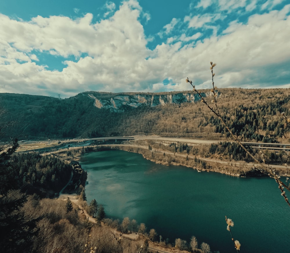 a lake surrounded by mountains under a cloudy blue sky