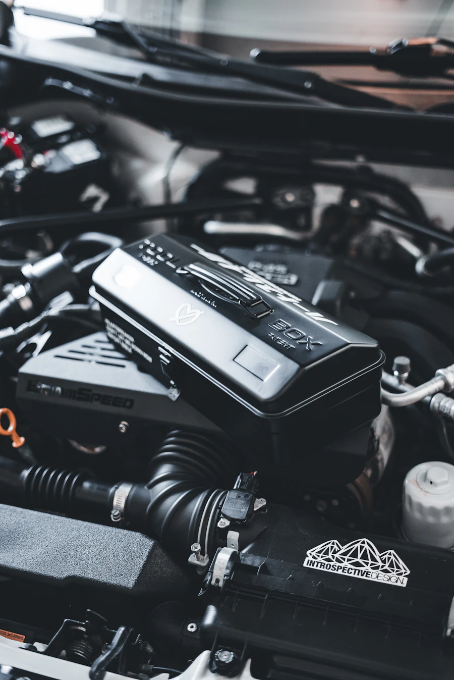 Diagnostic control module mounted in a car engine bay, surrounded by hoses and wiring.