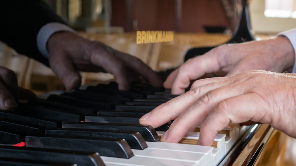 two hands are playing a piano together