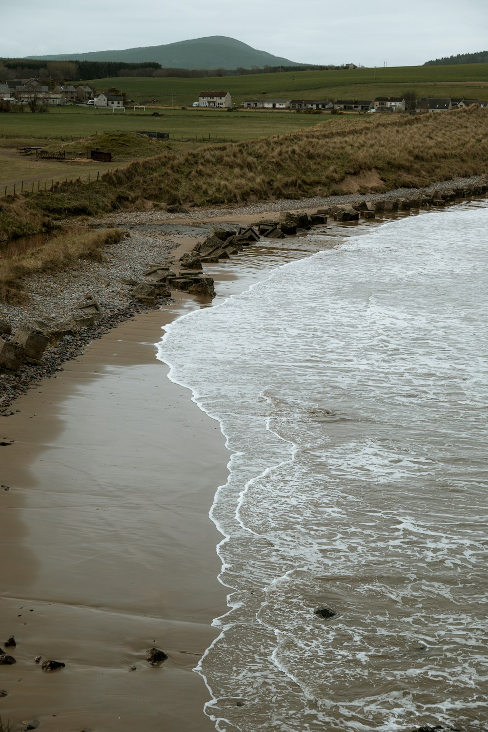 a body of water sitting on top of a sandy beach