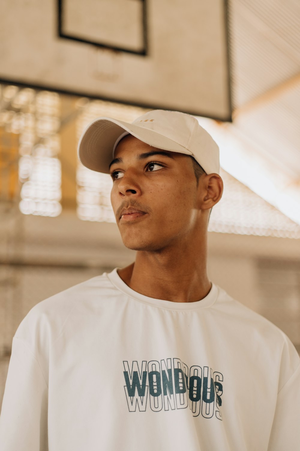 a young man wearing a white hat and a white t - shirt