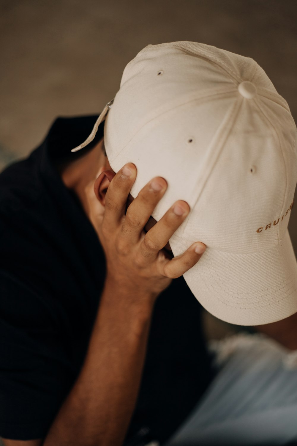 a man covering his face with a baseball cap
