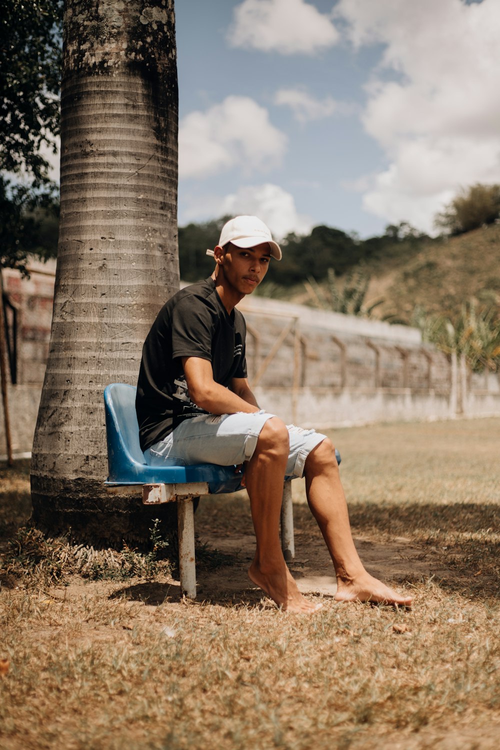 a man sitting on a blue bench next to a palm tree