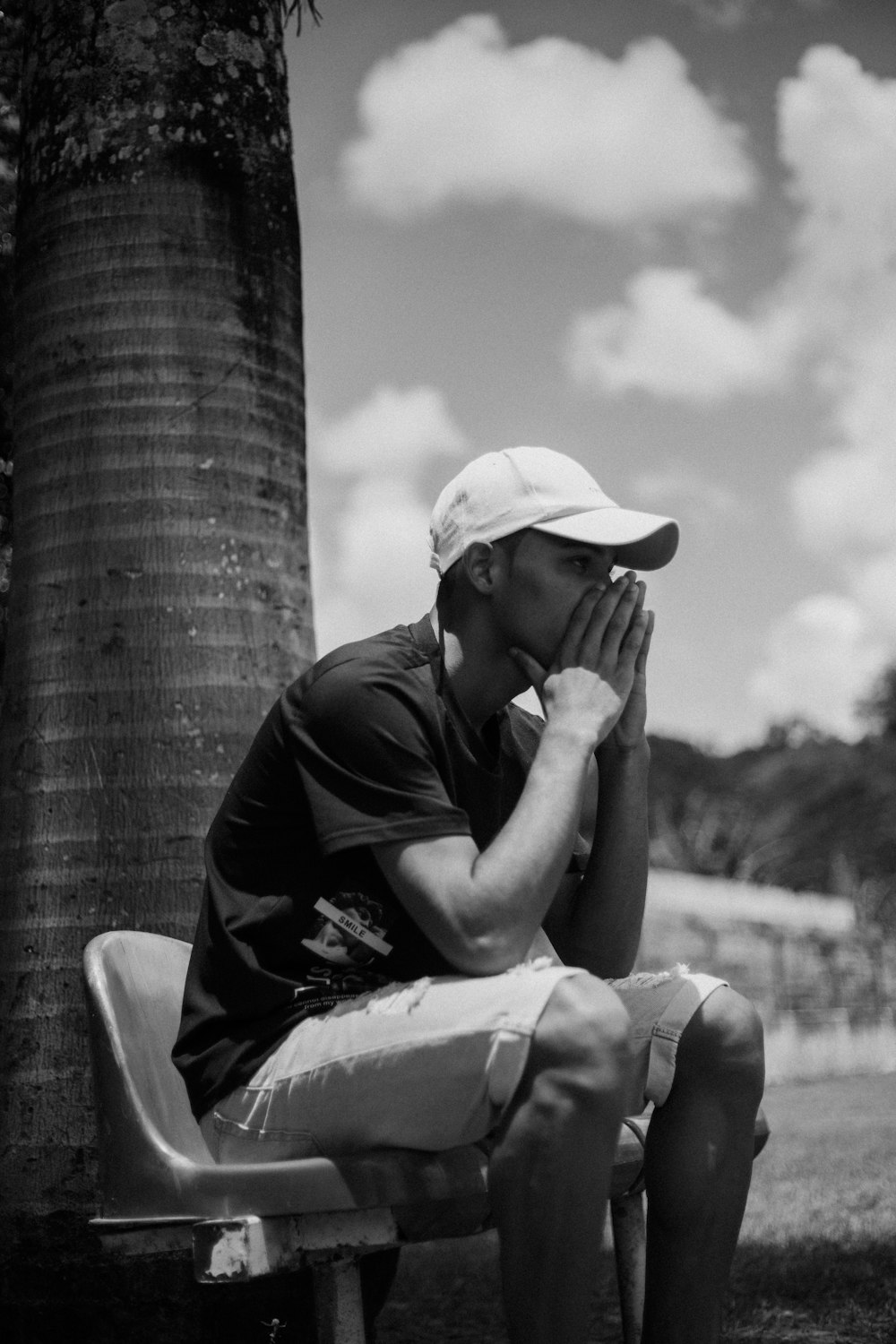 a man sitting on a bench next to a palm tree