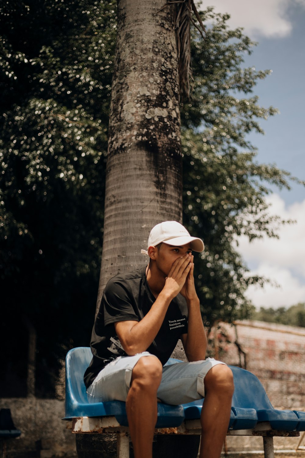 a man sitting on a blue bench next to a tree