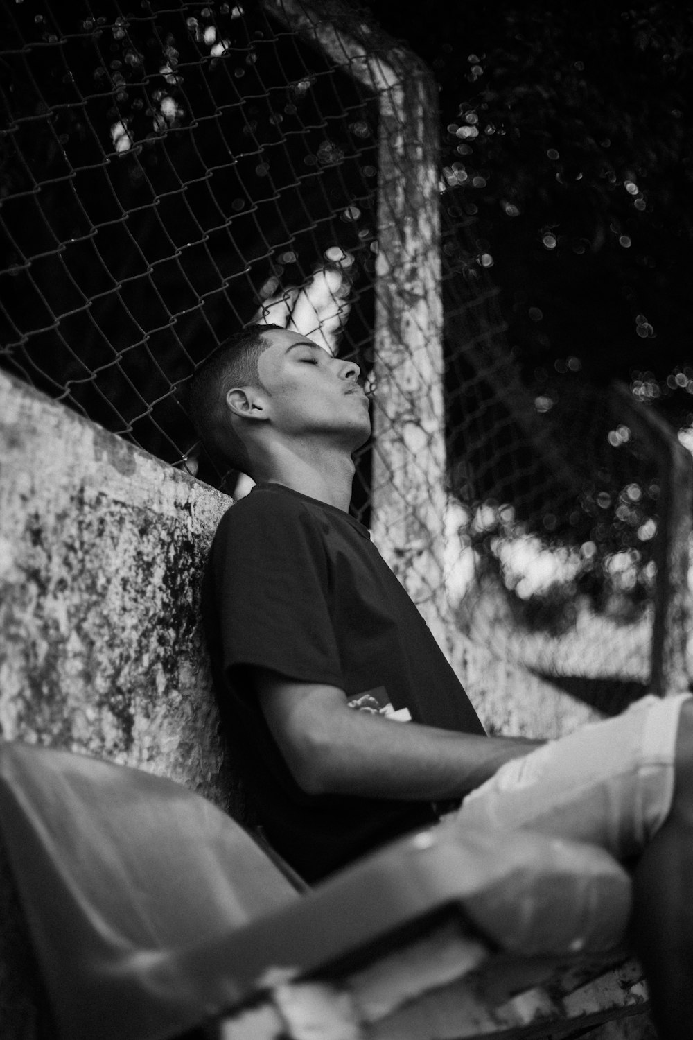 a young man sitting on the side of a wall