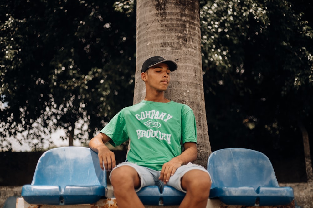 a man sitting on a bench next to a tree