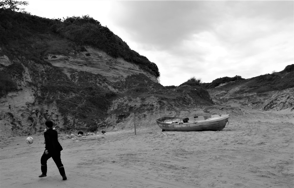 a person standing on a beach next to a boat