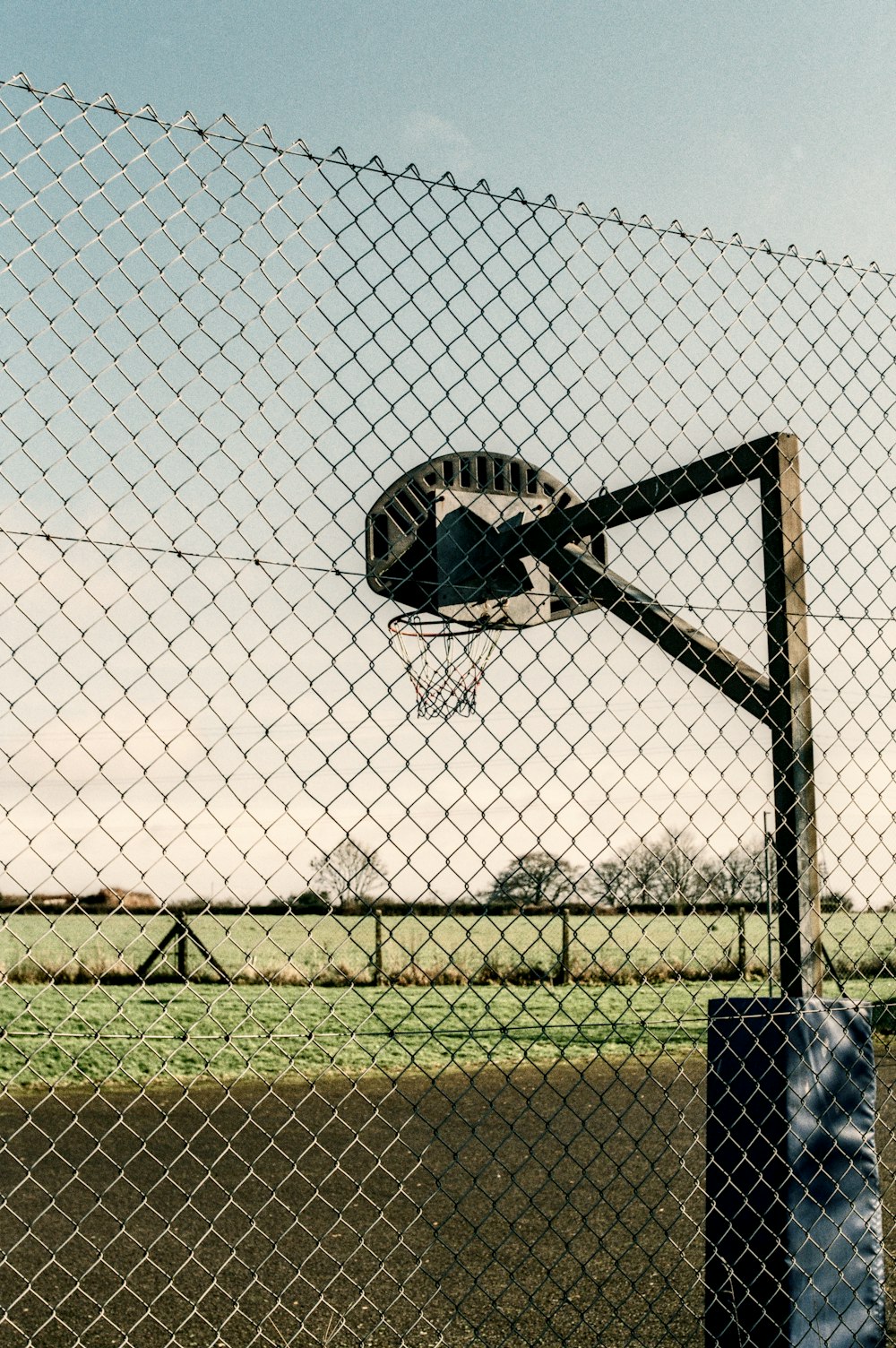 a basketball hoop is seen through a chain link fence