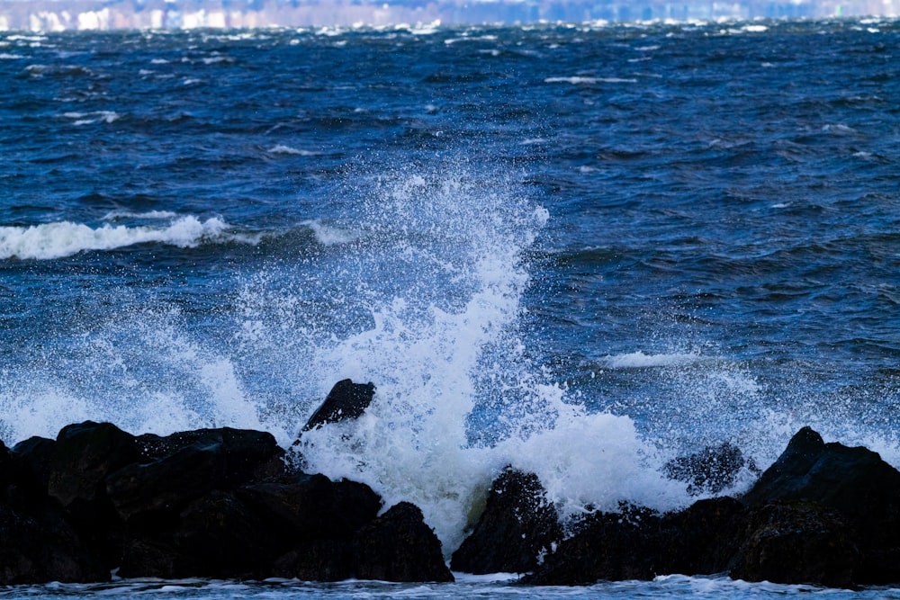 a wave crashes against the rocks in the ocean