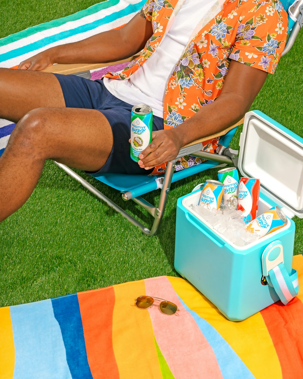 um homem sentado em uma cadeira de gramado ao lado de um cooler