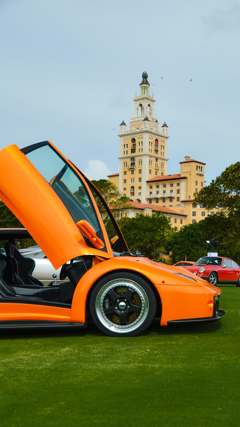 an orange sports car parked in the grass