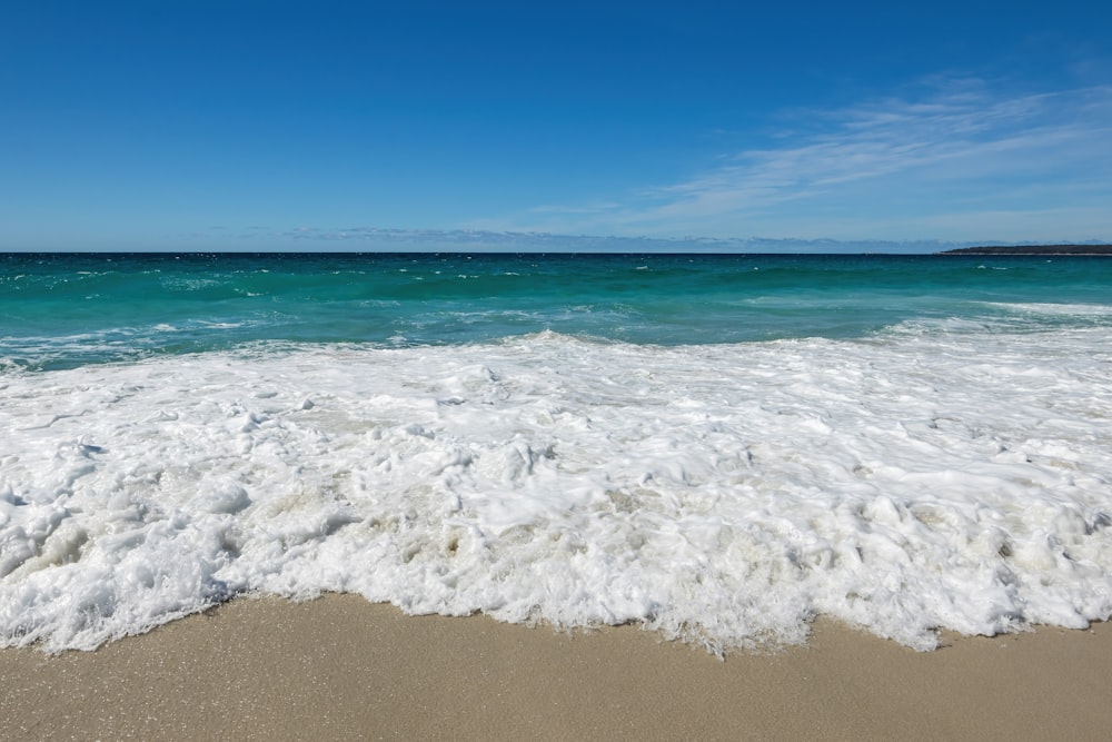 a sandy beach with waves coming in and out of the water