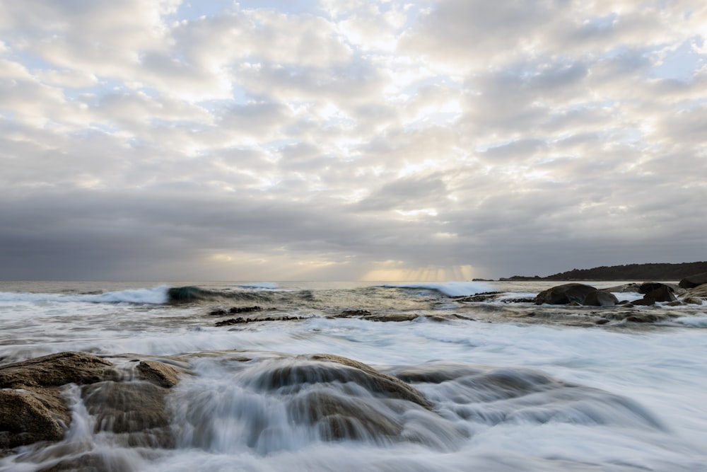 un cuerpo de agua rodeado de rocas bajo un cielo nublado