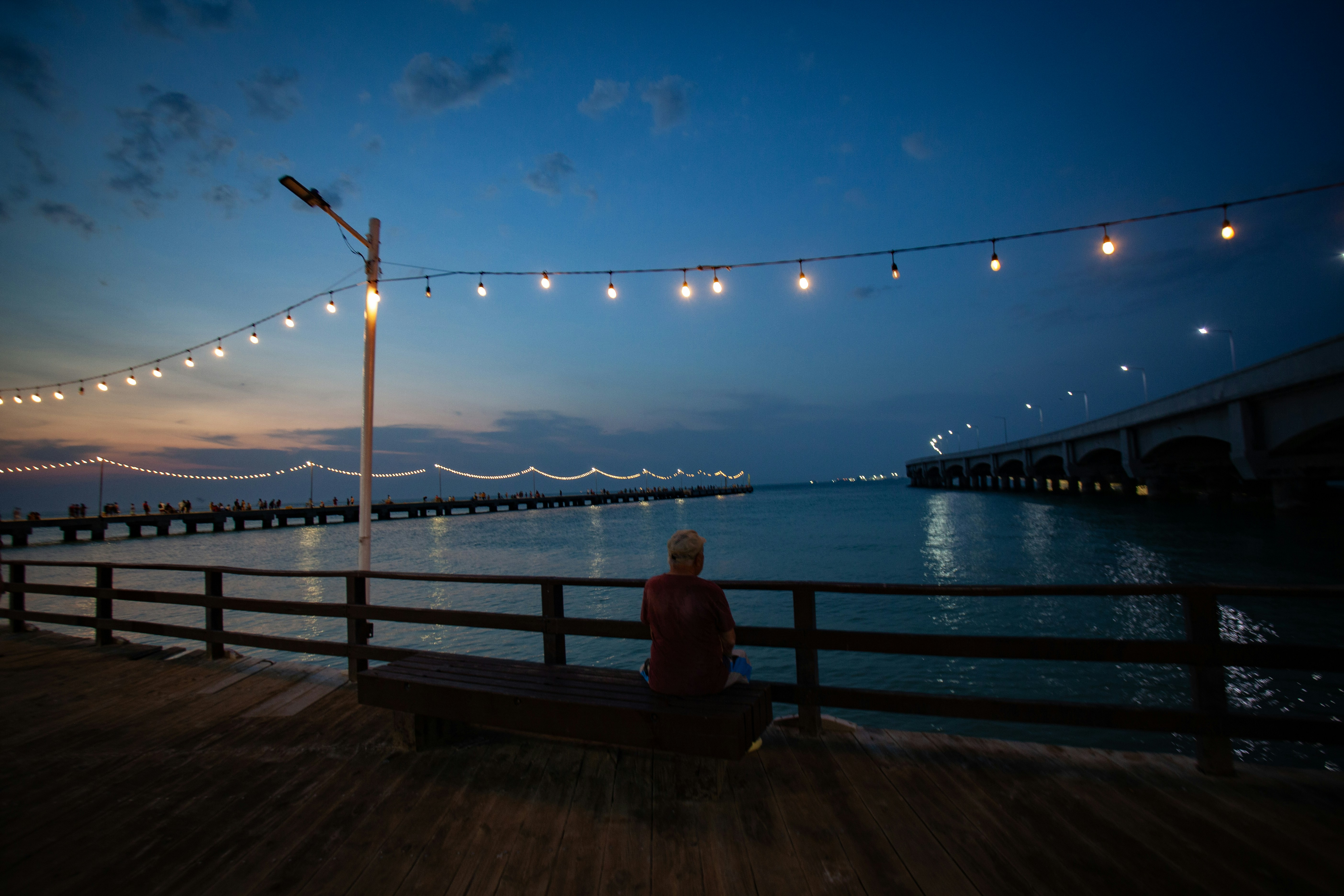 Fotomural a person sitting on a bench near the water