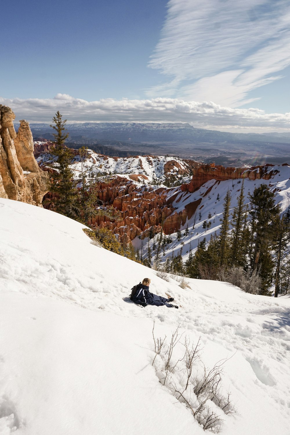 a person sitting on top of a snow covered slope
