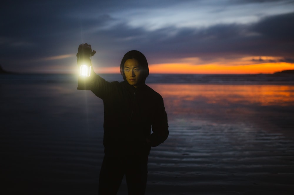 une personne debout sur une plage tenant une lumière