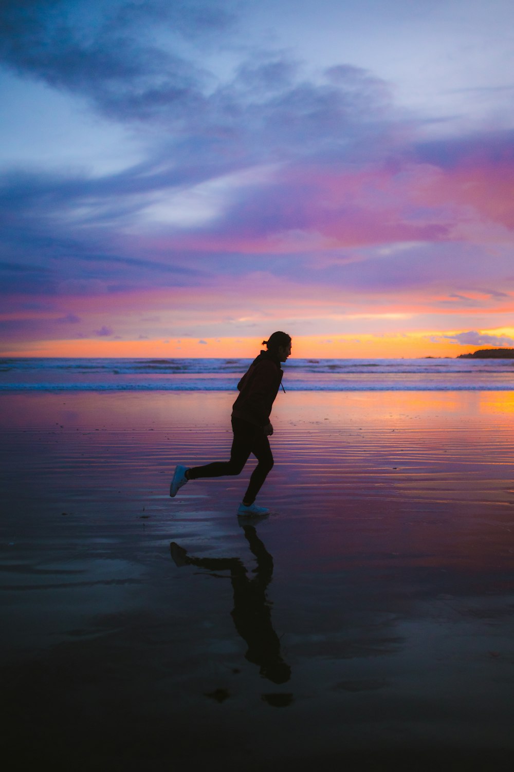 uma pessoa correndo em uma praia ao pôr do sol