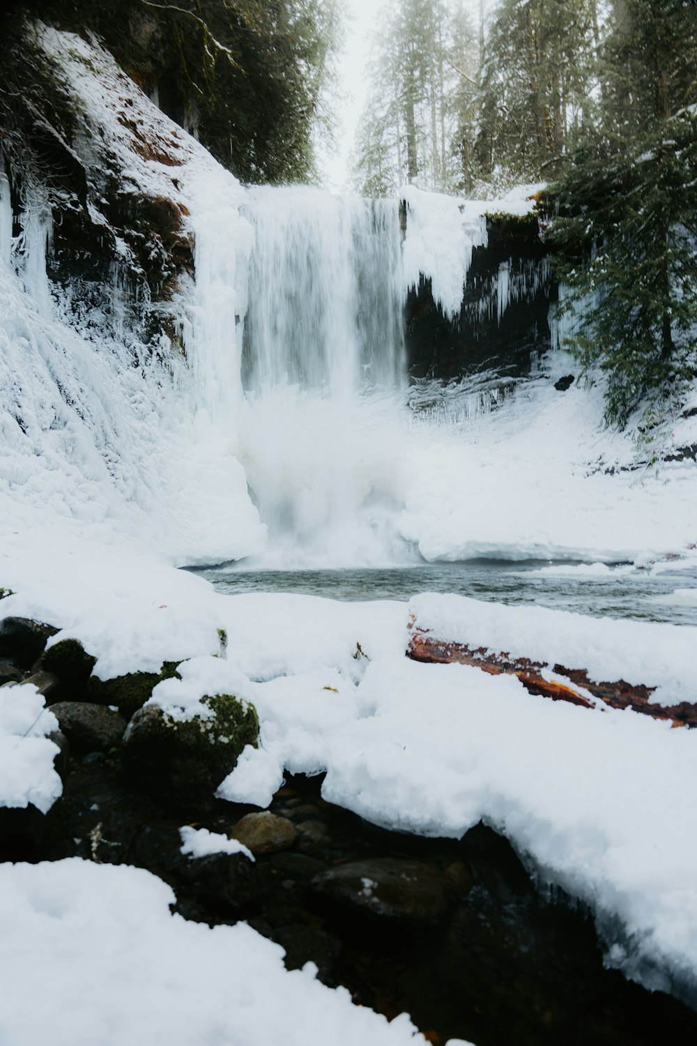a frozen waterfall with snow on the ground