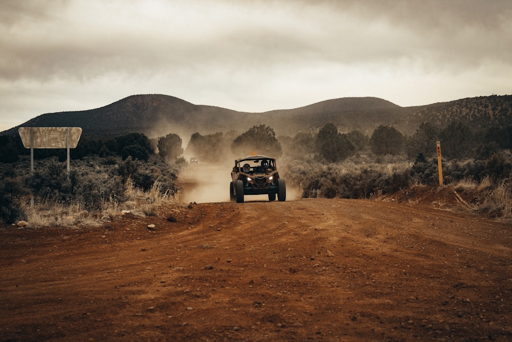 a jeep driving down a dirt road near a forest