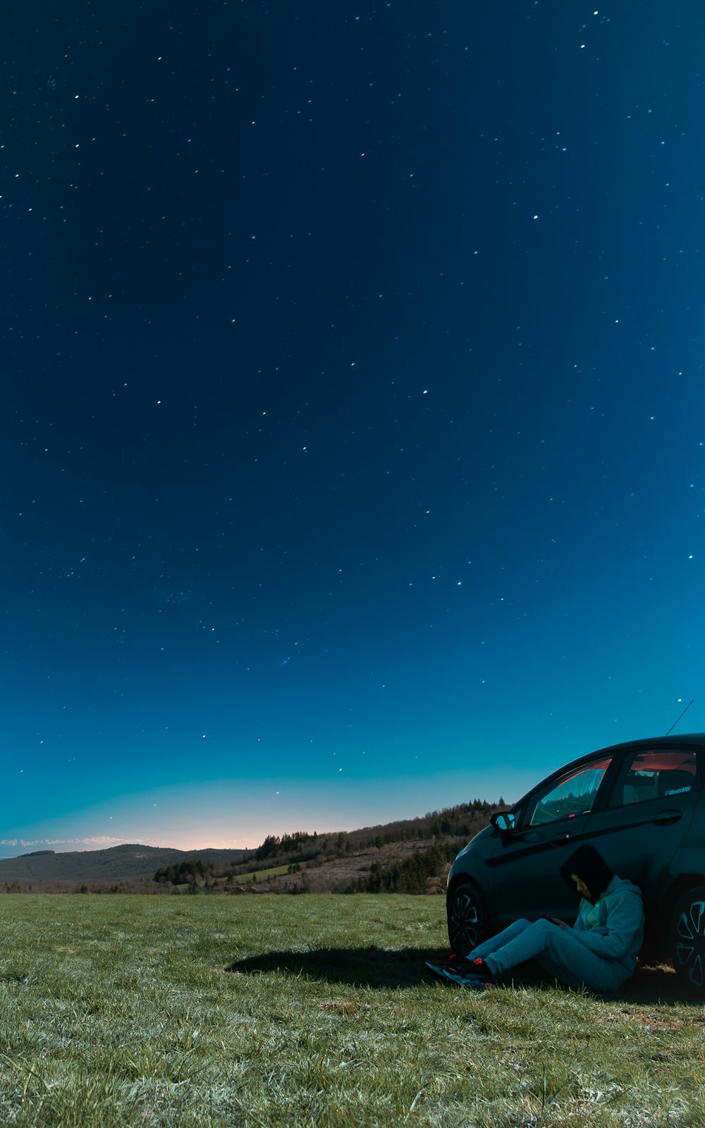 a car parked in a field under a night sky