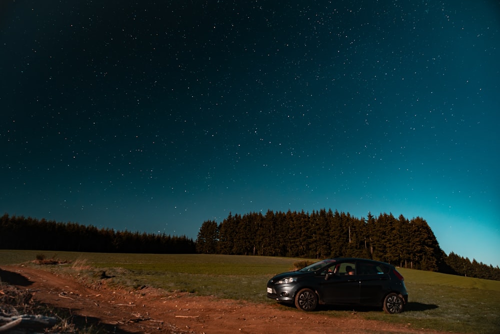 a car parked on a dirt road under a night sky