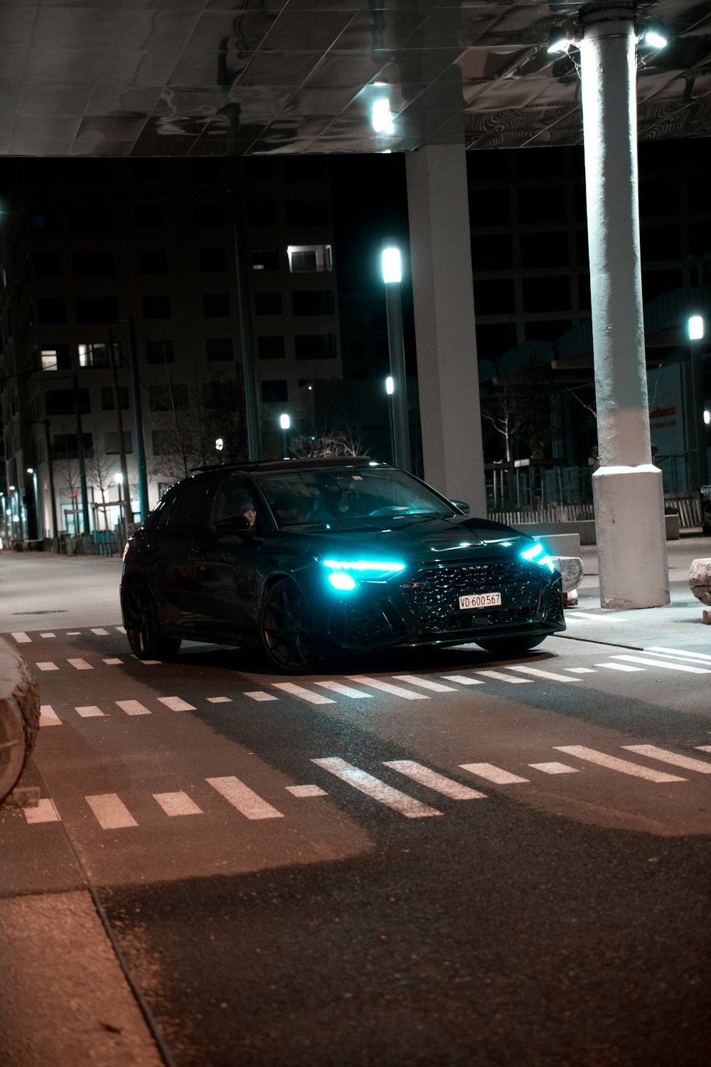 a black car driving down a street at night