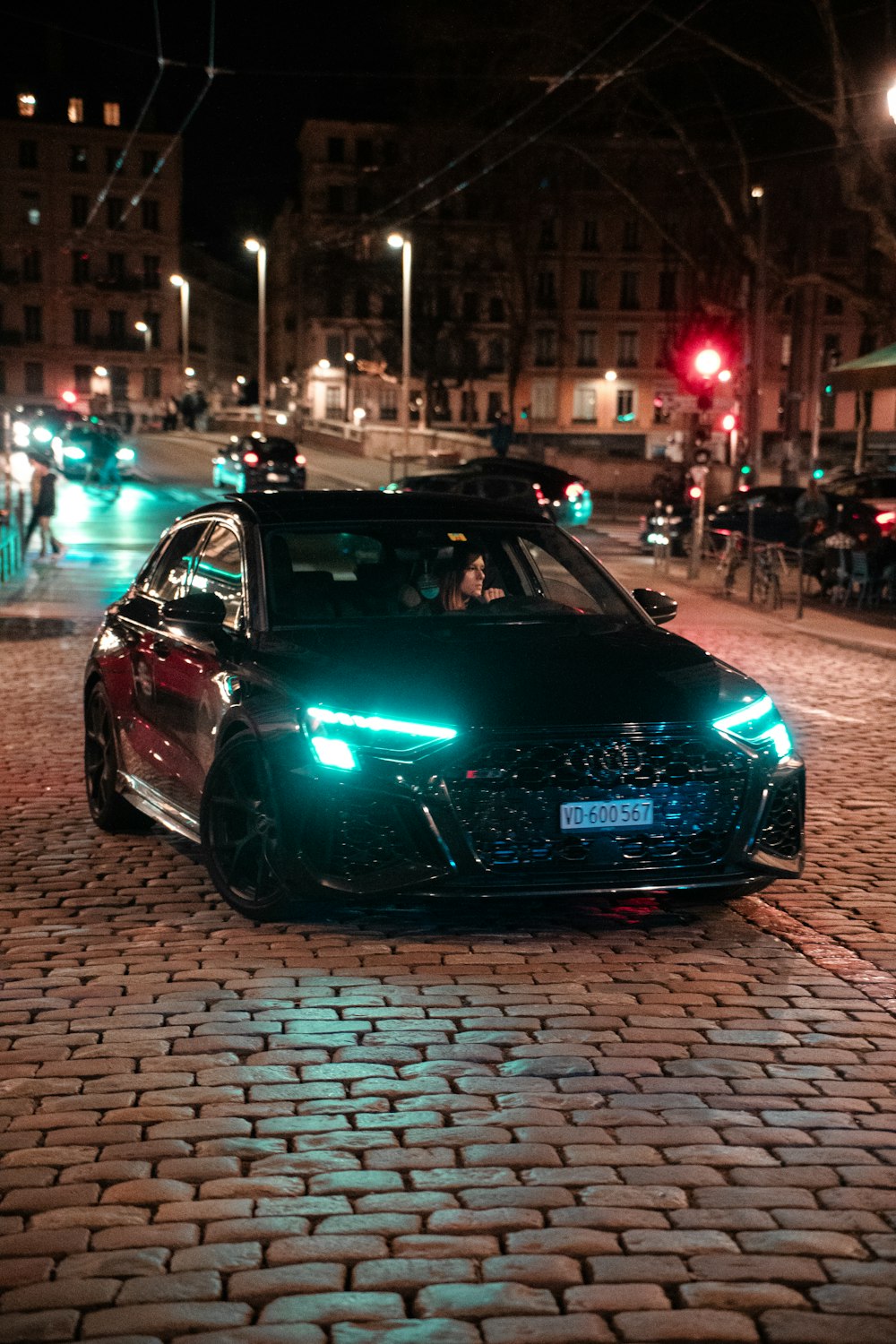 a car is parked on a cobblestone street at night