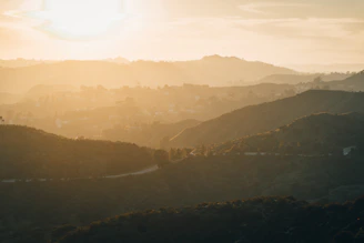 the sun is setting over the hills in the distance