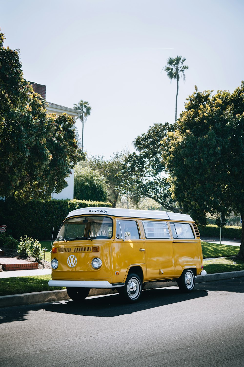 a yellow van driving down a street next to trees