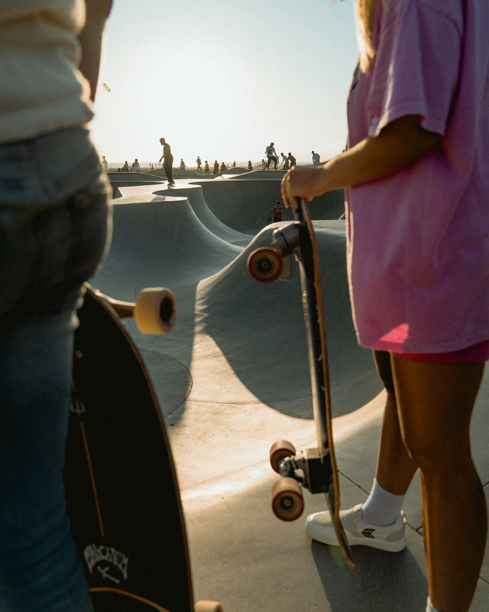 Ein Mädchen in einem rosa Kleid hält ein Skateboard in der Hand