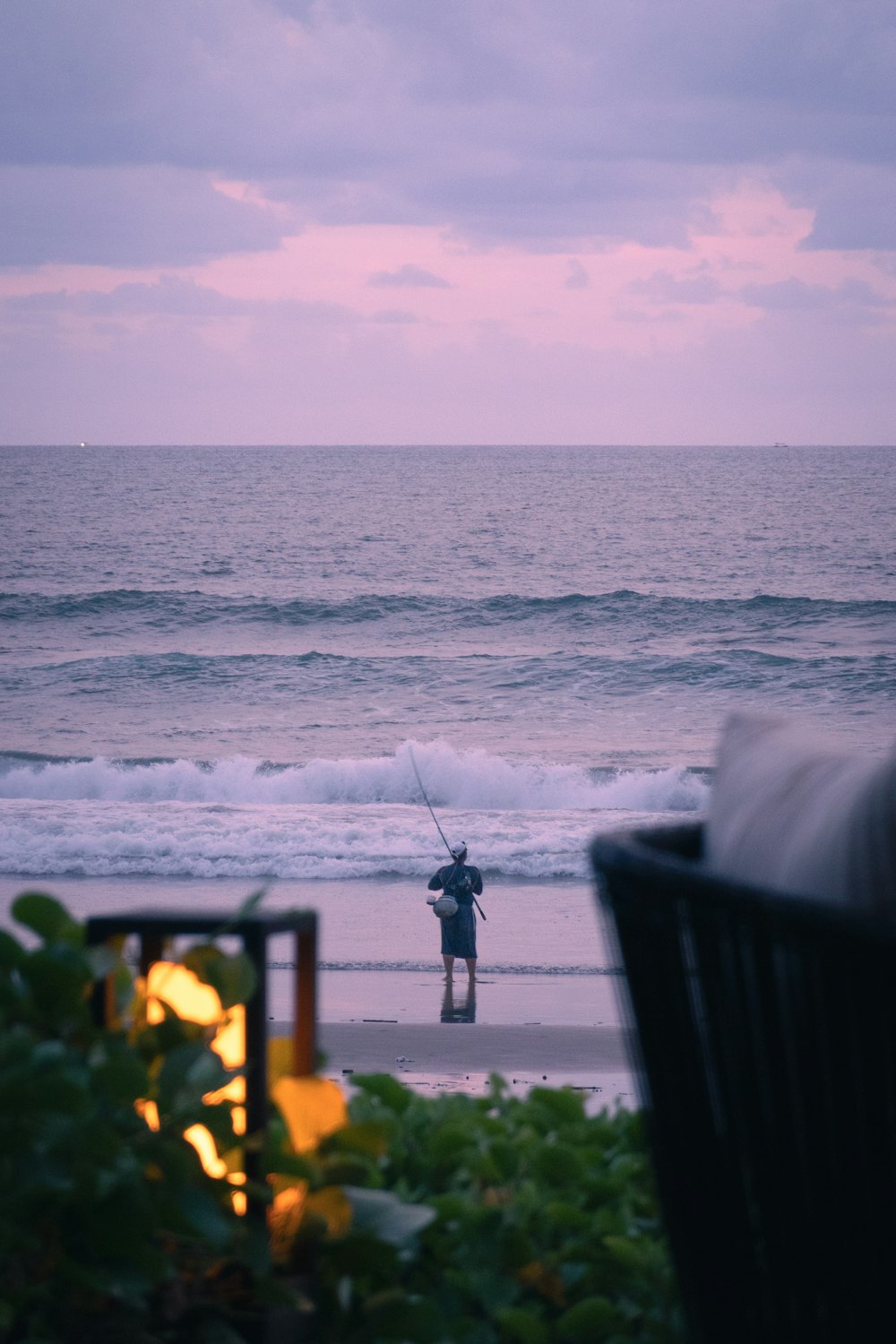 a man standing on a beach holding a fishing pole