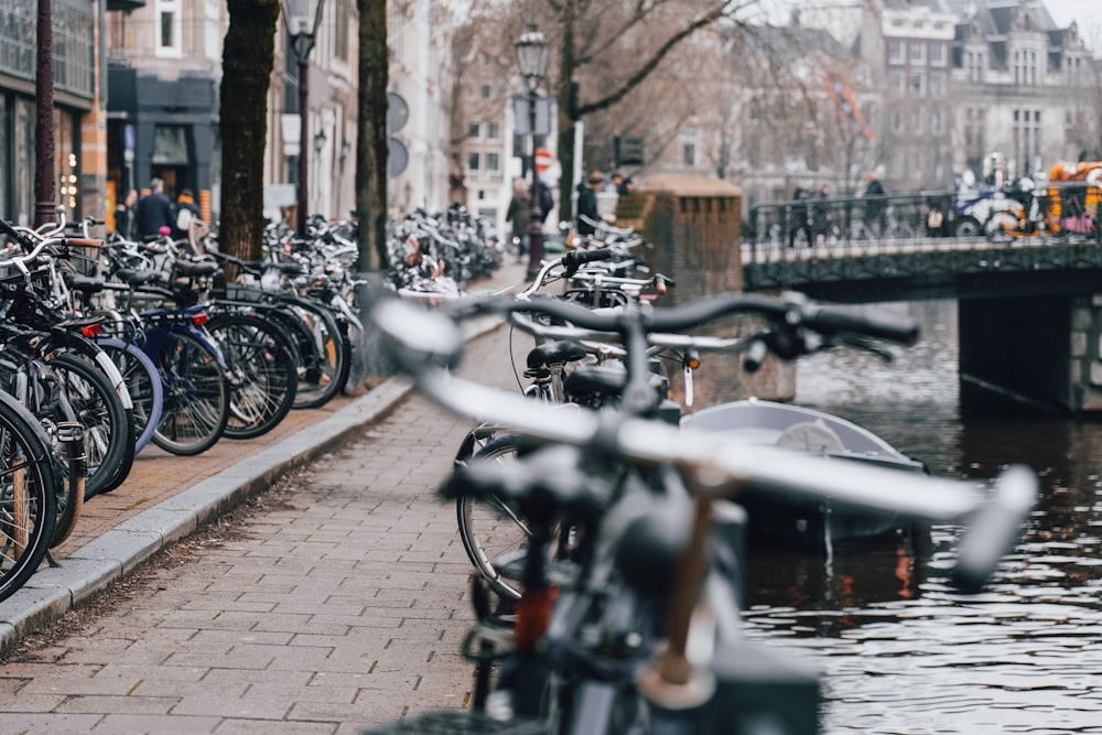 a bunch of bikes parked on the side of a river