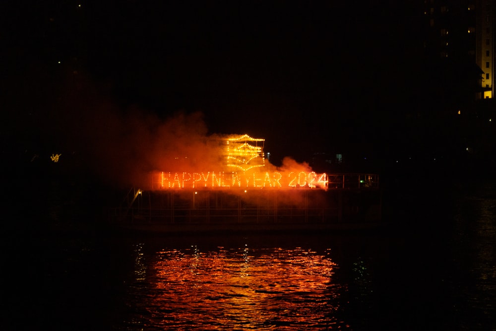 a boat is lit up in the dark with a sign that says happy new year