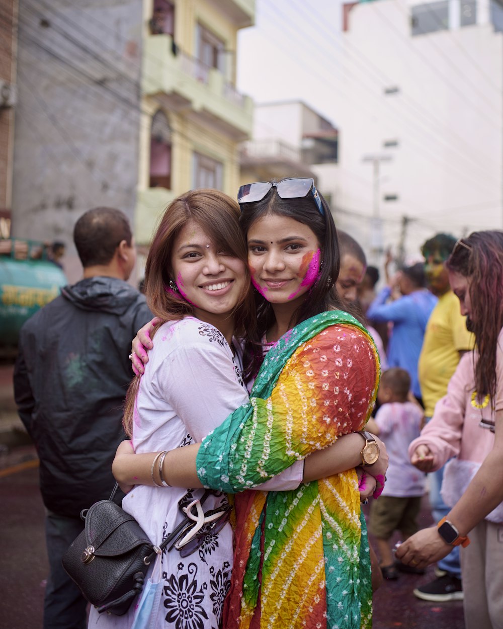 two young women hugging each other in the street