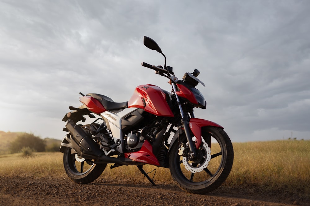 a red motorcycle parked on a dirt road