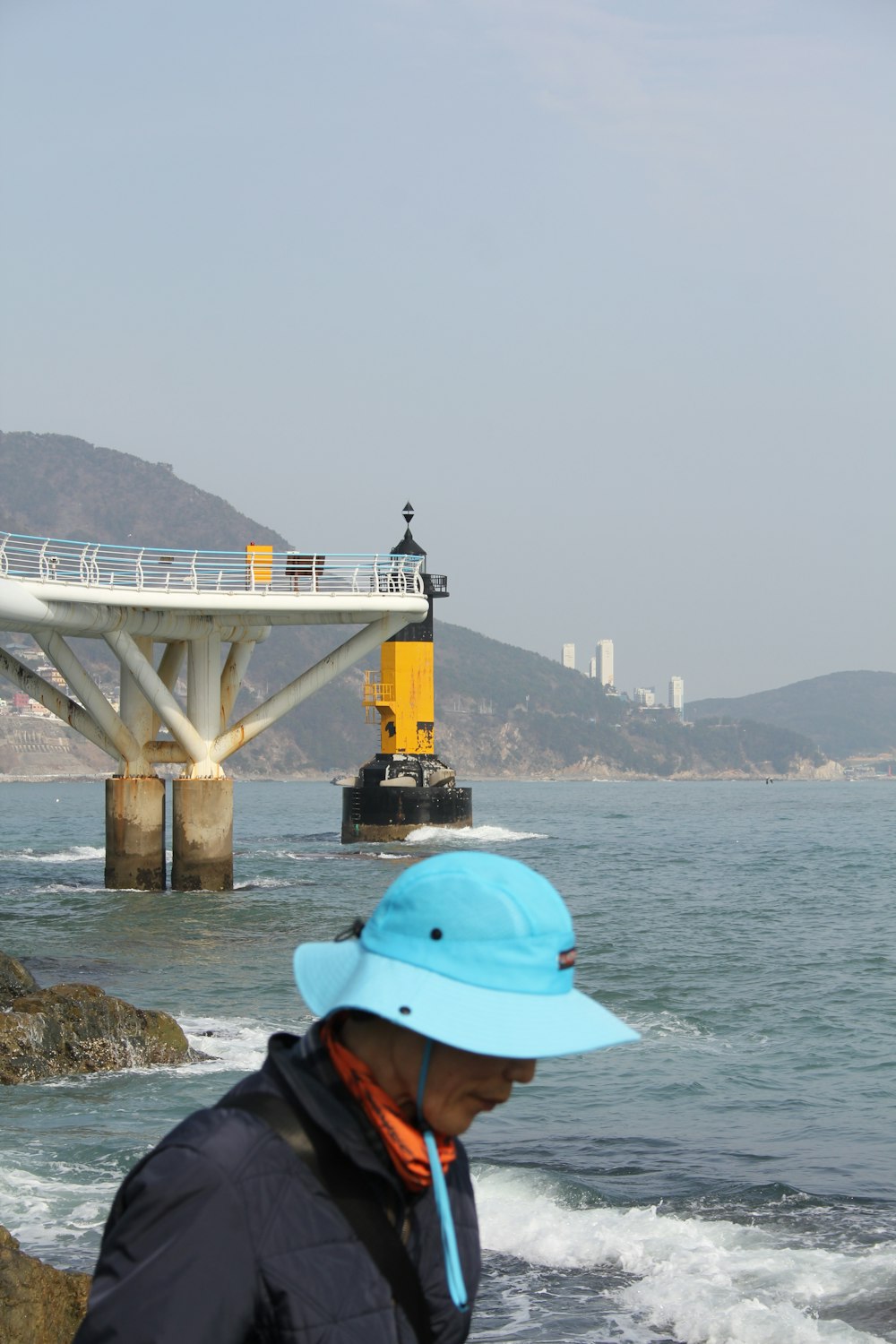 a man wearing a blue hat standing in front of a body of water