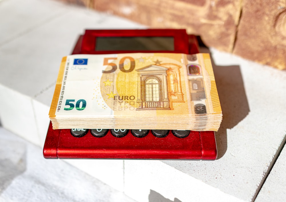 a 50 euro bill sitting on top of a red machine