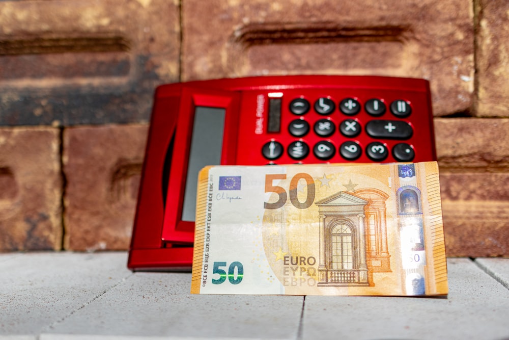 a 50 euro bill sitting next to a red telephone
